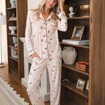 Modal wearing Long-Sleeved Women's Pajama Set in Book Club print standing against a book shelf