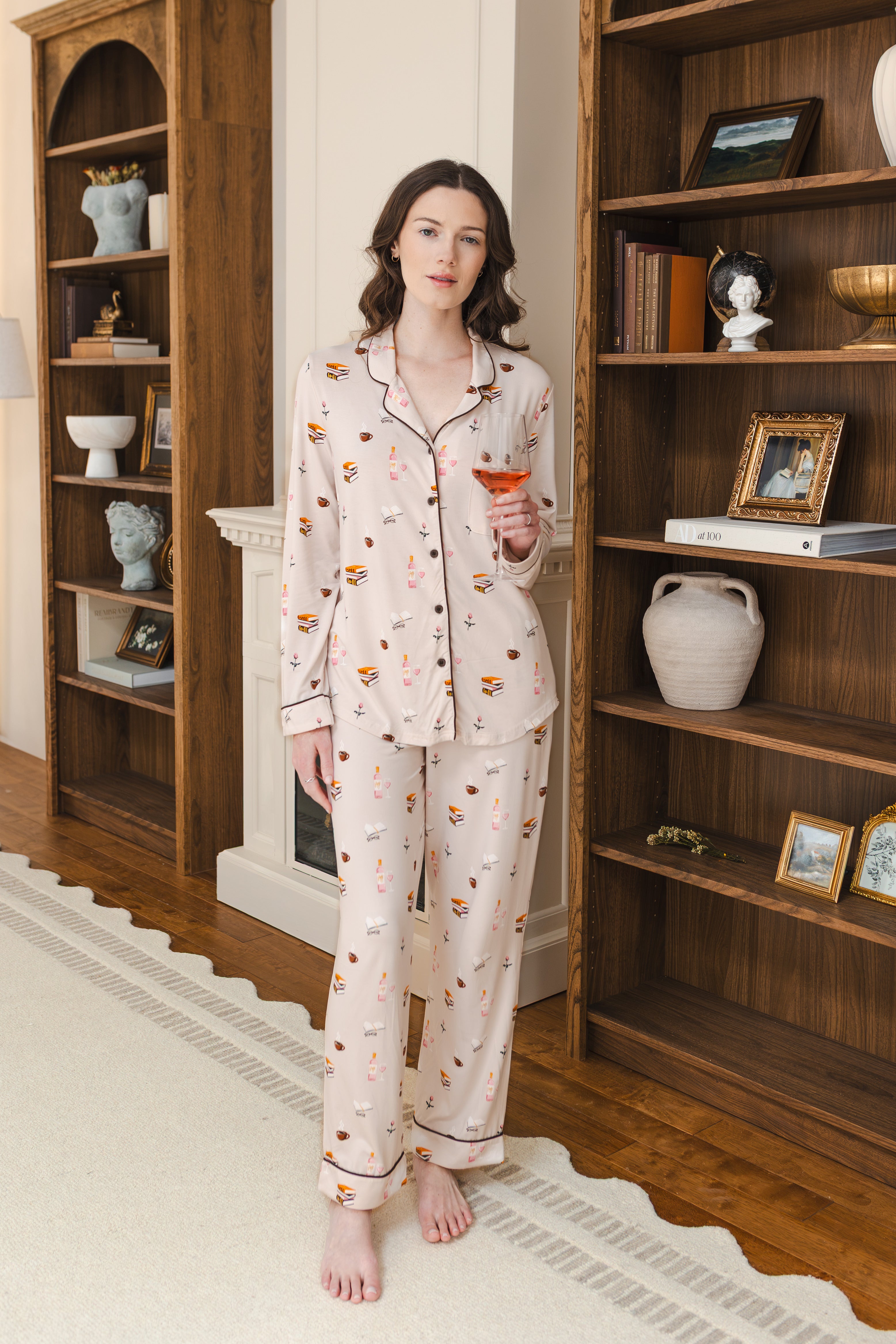 Modal wearing Long-Sleeved Women's Pajama Set in Book Club print posing in a study holding a drink in hand
---PJ 4