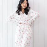 Woman wearing a white bow print robe against a white wooden panel background