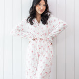 Woman wearing a white bow print robe against a white wooden panel background