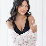 Woman wearing a black top and white pink bow robe against a white background