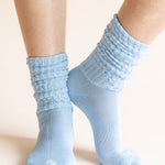 Light blue ribbed crew socks worn on a person's feet, shown against a plain warm beige background.