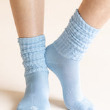 Light blue ribbed crew socks worn on a person's feet, shown against a plain warm beige background.
