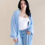 Female model posing wearing the Chunky Knit Women's Oversized Cardigan in Breeze over a white tank top and light wash jeans