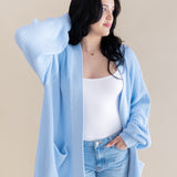Female model posing wearing the Chunky Knit Women's Oversized Cardigan in Breeze with a white shirt and light wash jeans