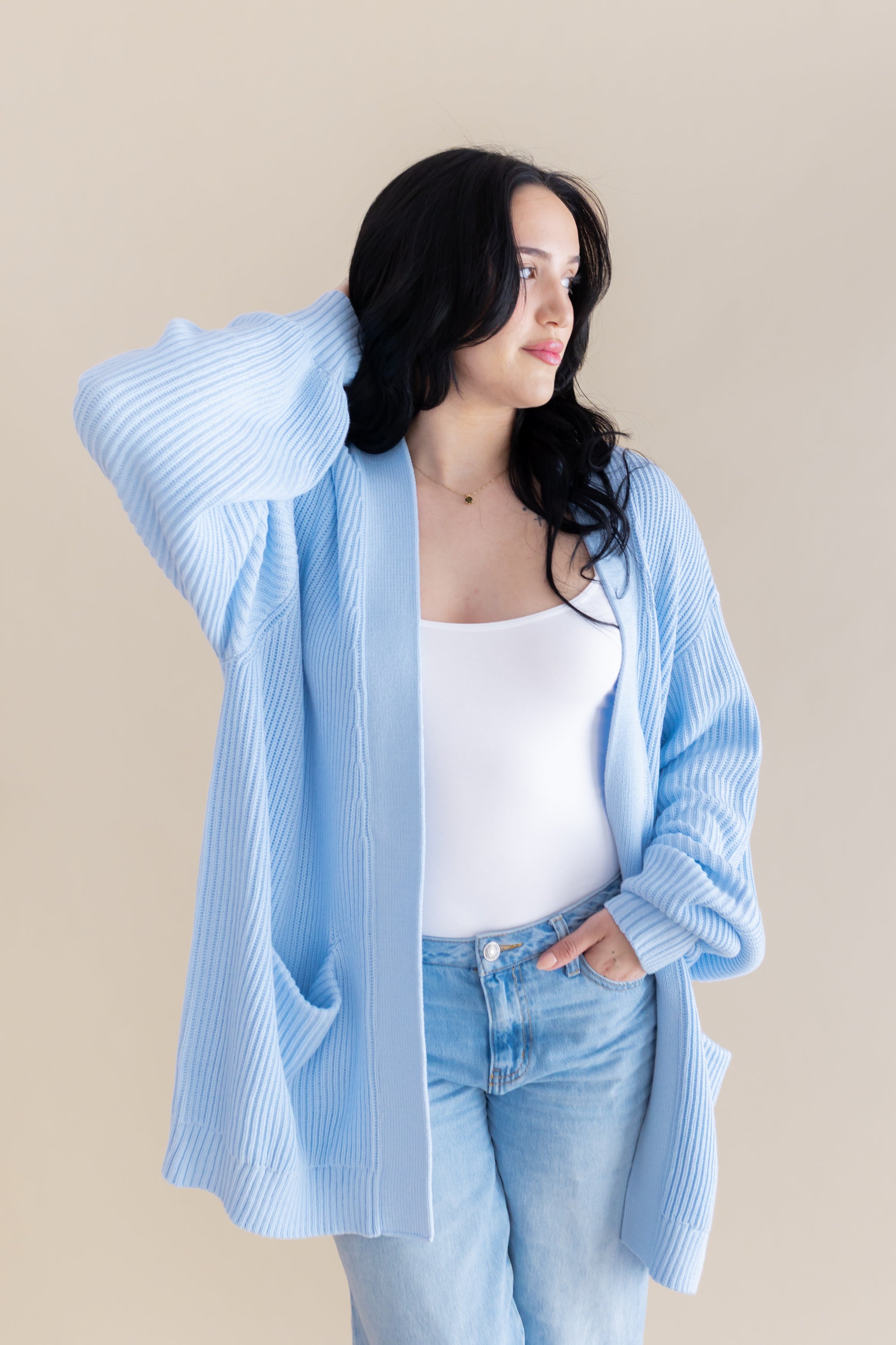 Female model posing wearing the Chunky Knit Women's Oversized Cardigan in Breeze with a white shirt and light wash jeans