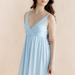 Woman wearing a light blue nightgown against a beige background
