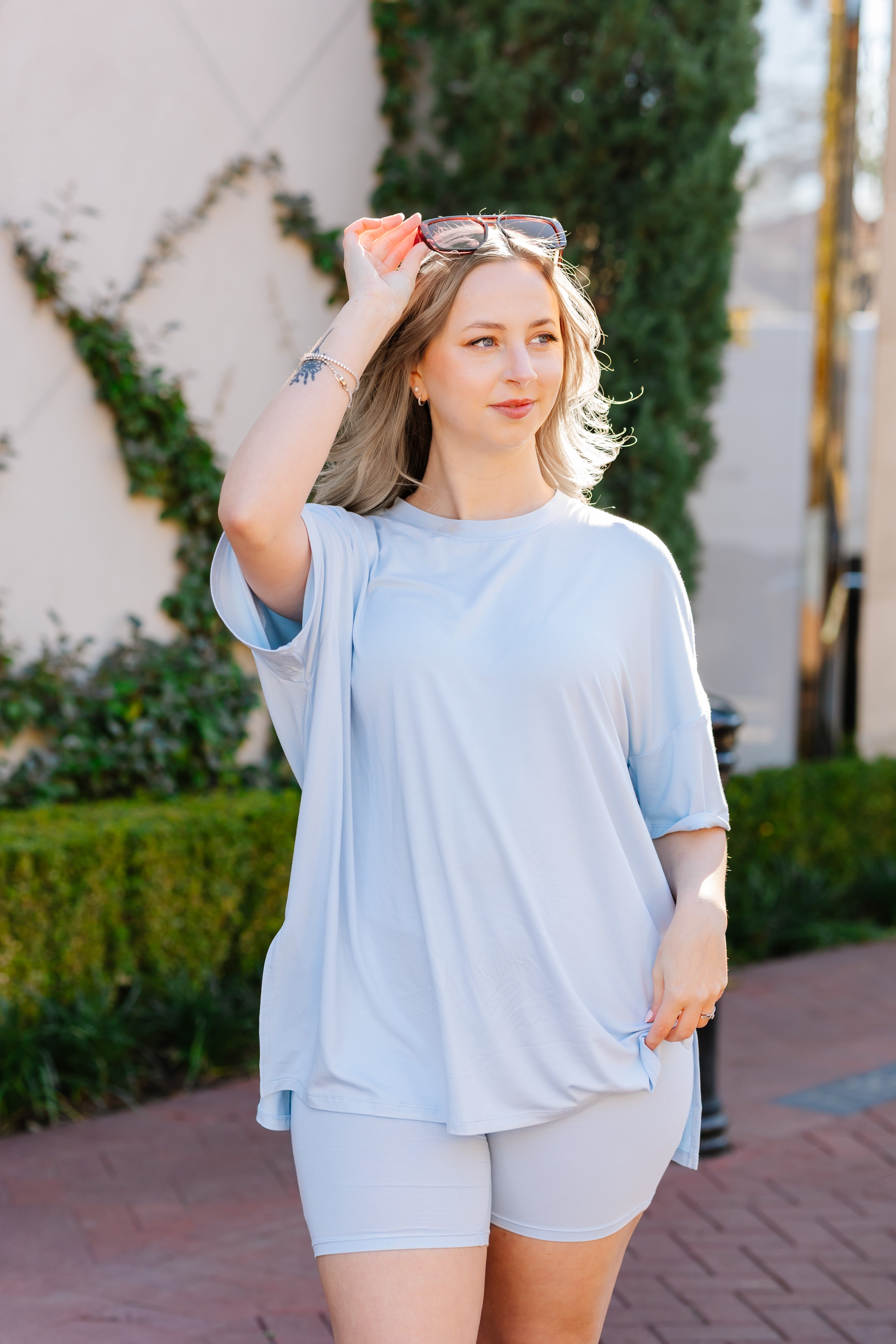 Woman wearing the Biker Short Set in Breeze in an outdoor setting with sunglasses on her head  ::: Model is 5'2" wearing size S ///