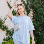 Model standing infront of a stone wall with greenery while wearing the Biker Short Set in Breeze 