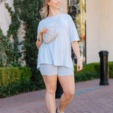 Woman modeling the Biker Short Set in Breeze paired with sneakers and cross body bag