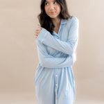 Woman wearing a light blue shirt dress against a beige background