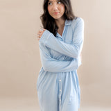 Woman wearing a light blue shirt dress against a beige background