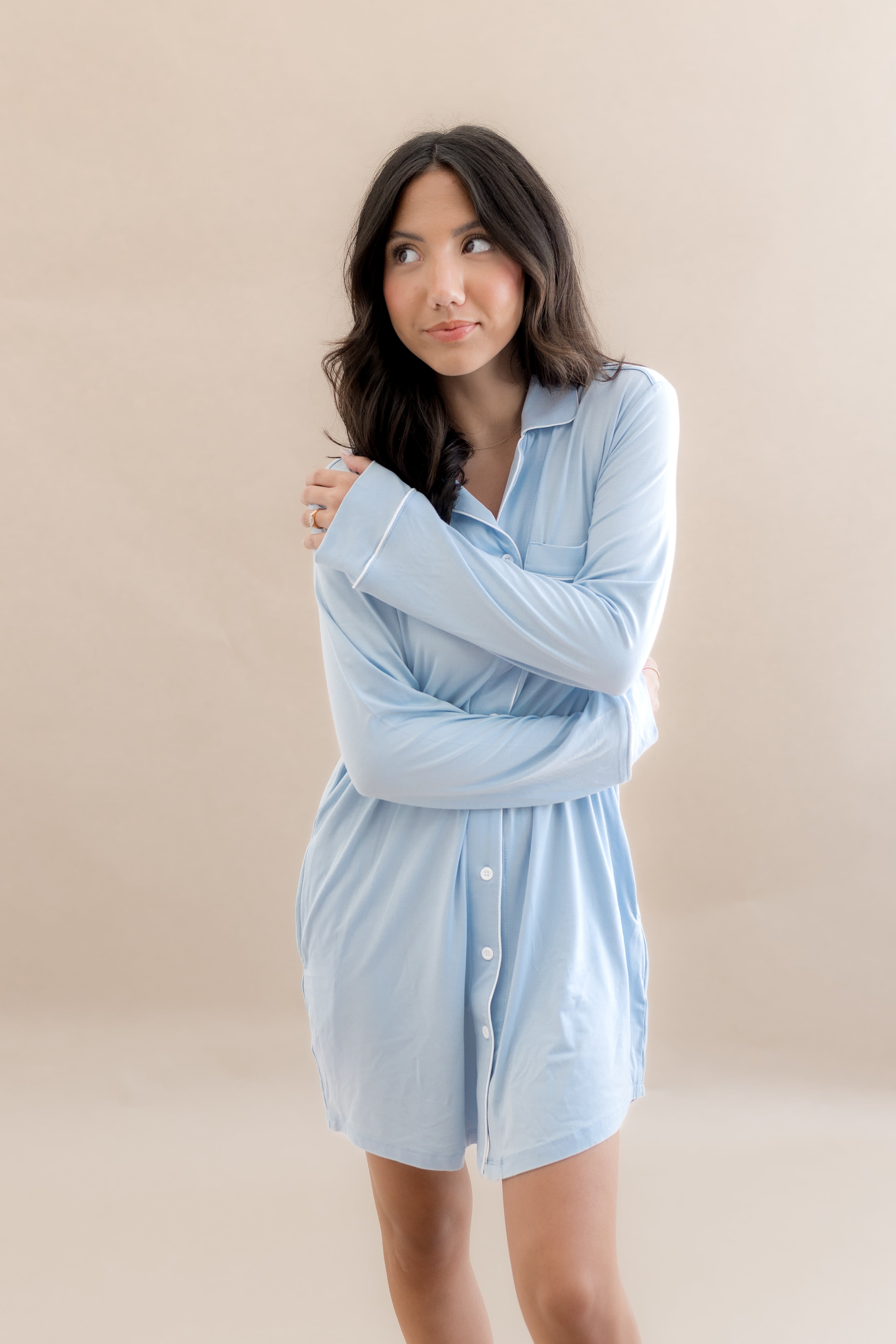 Woman wearing a light blue shirt dress against a beige background