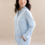 Woman wearing a light blue shirt dress against a beige background
