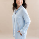 Woman wearing a light blue shirt dress against a beige background