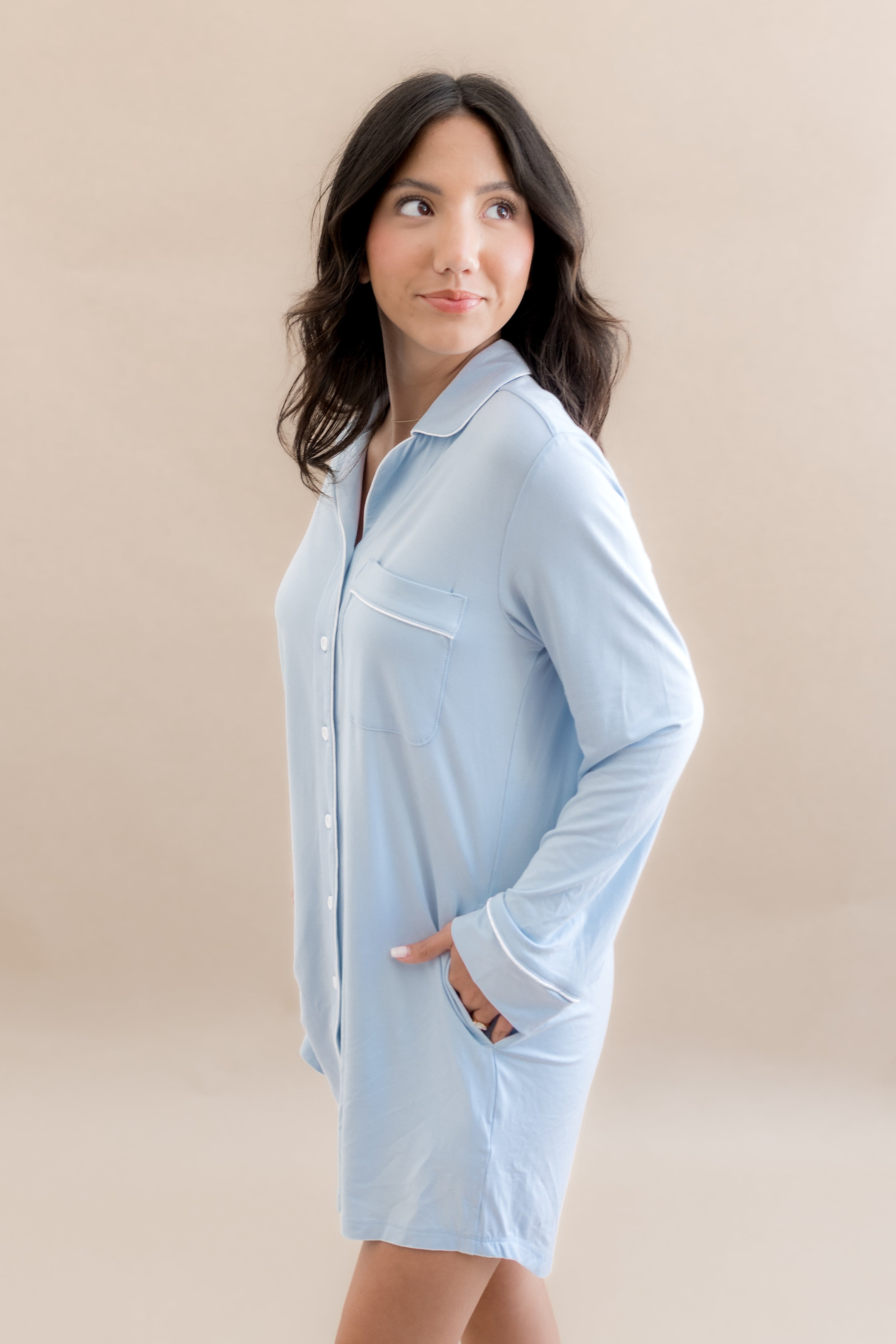 Woman wearing a light blue shirt dress against a beige background