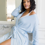 Woman wearing a light blue robe in a bathroom setting