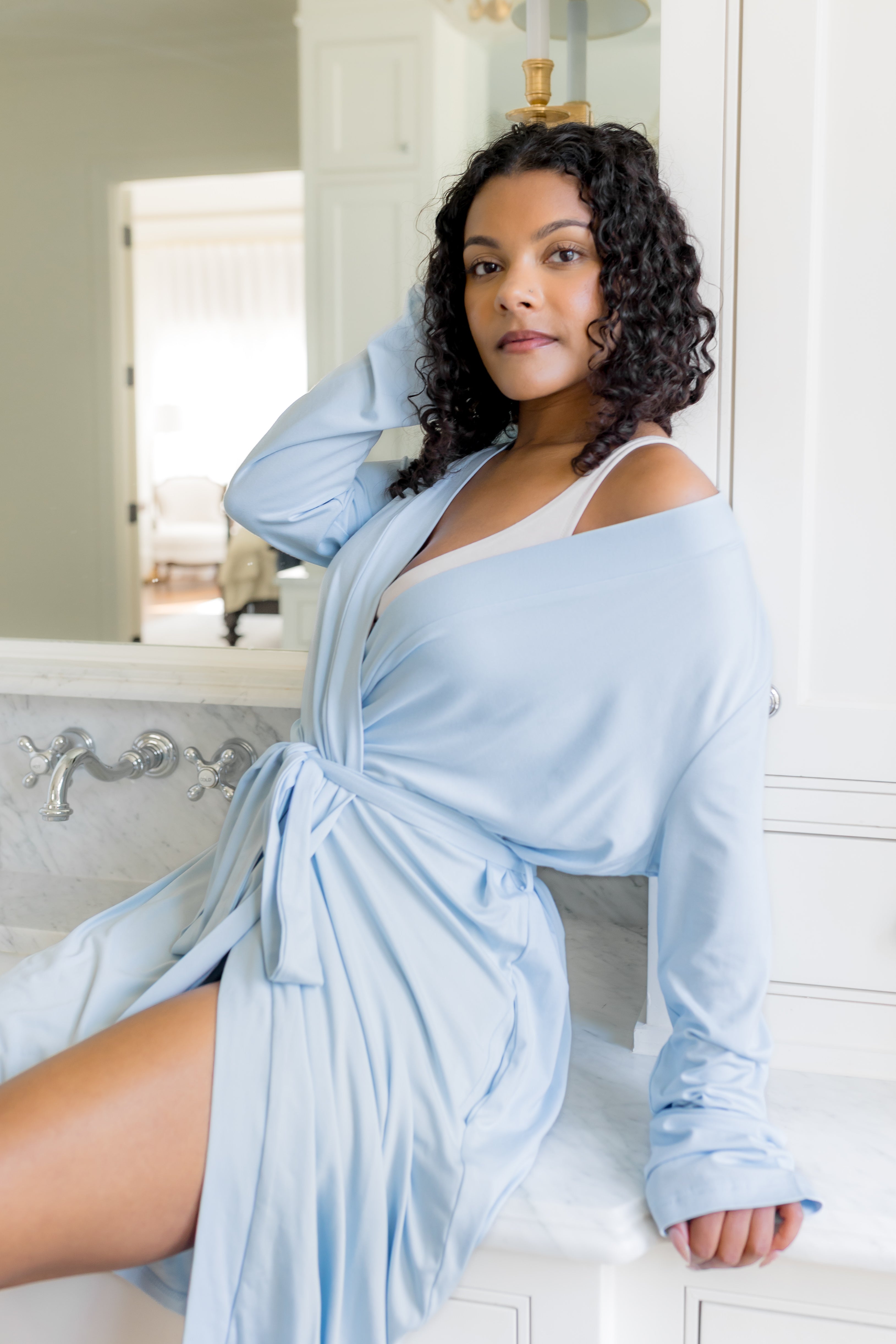 Woman wearing a light blue robe in a bathroom setting