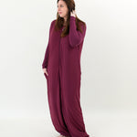 Woman looking to the side with one hand in her hair while wearing an Adult Sleep Bag Walker in Burgundy with matching top underneath it