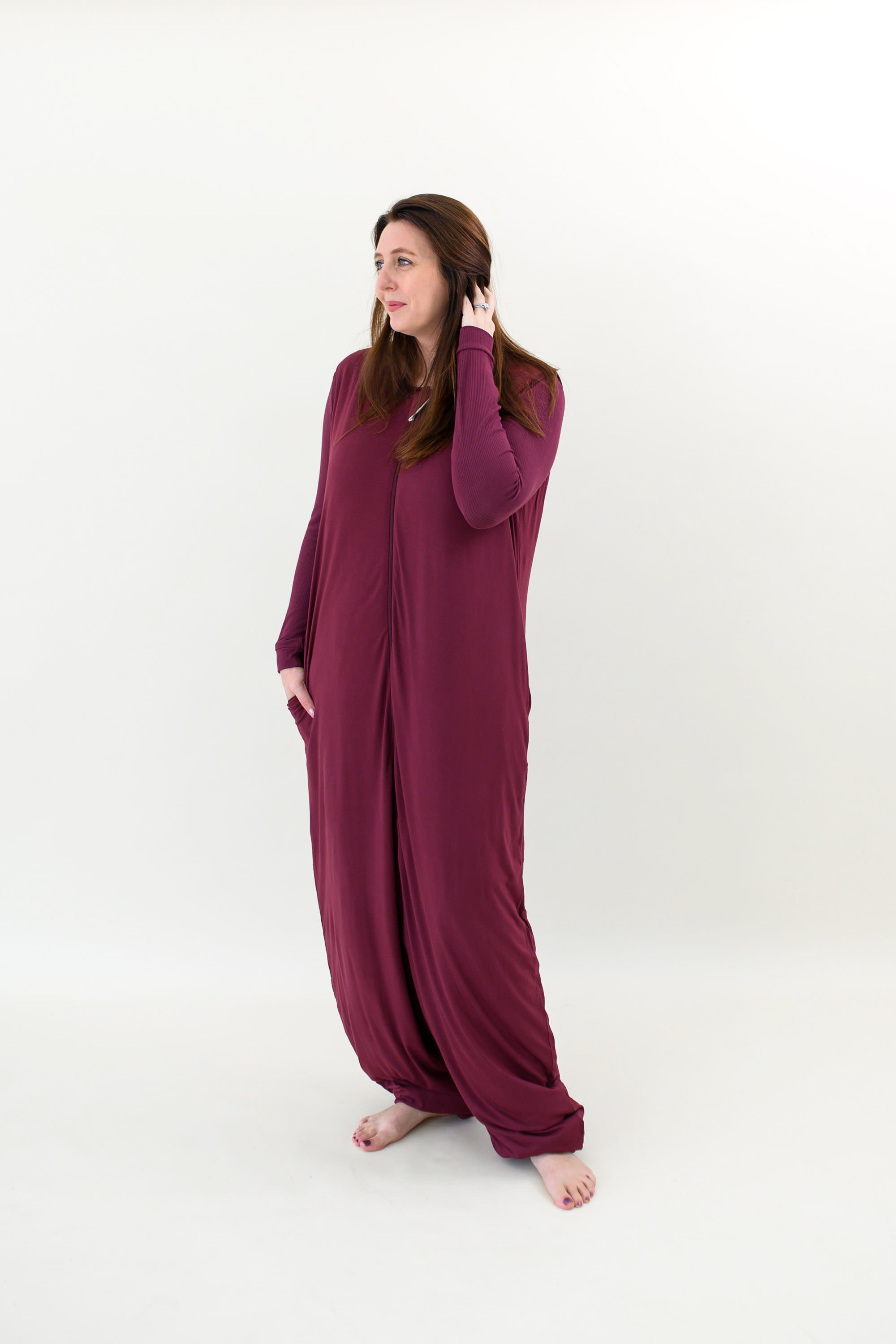 Woman looking to the side with one hand in her hair while wearing an Adult Sleep Bag Walker in Burgundy with matching top underneath it