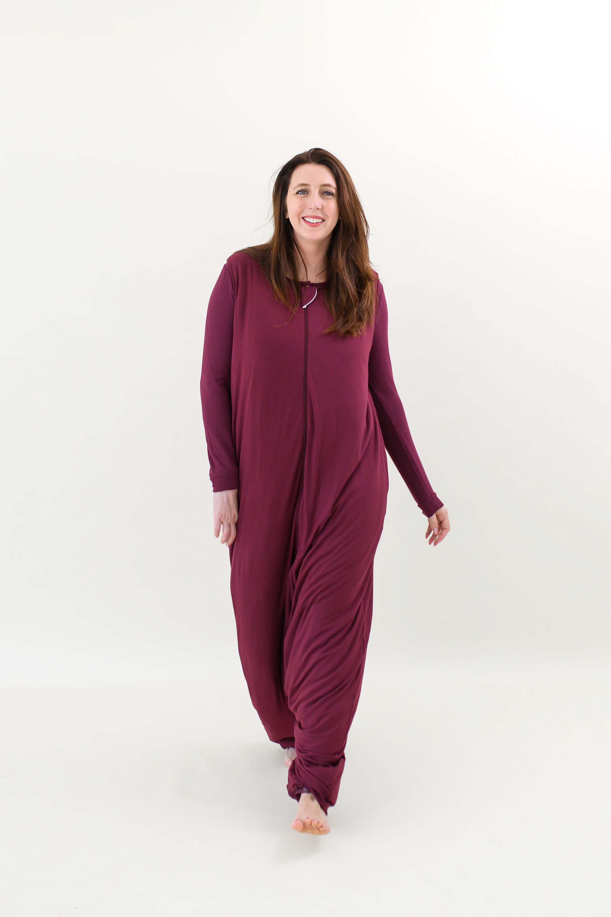 Smiling model walking towards camera while wearing the Adult Sleep Bag Walker in Burgundy 