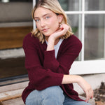 Modal posing outdoors wearing Chunky Knit Women's Waffle Cardigan in Burgundy over white t-shirt and blue jeans