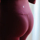 The back of the Bamboo Flex Women’s Leggings in Burgundy shown on a model with the Kyte baby logo visible on the back waistband