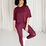 Female standing on one foot with the other foot resting against her leg wearing the Bamboo Flex Women’s Leggings in Burgundy and matching short sleeve tee