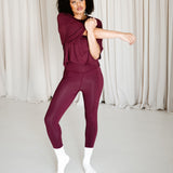 Female model stretching wearing the Bamboo Flex Women’s Leggings in Burgundy and matching short sleeve tee