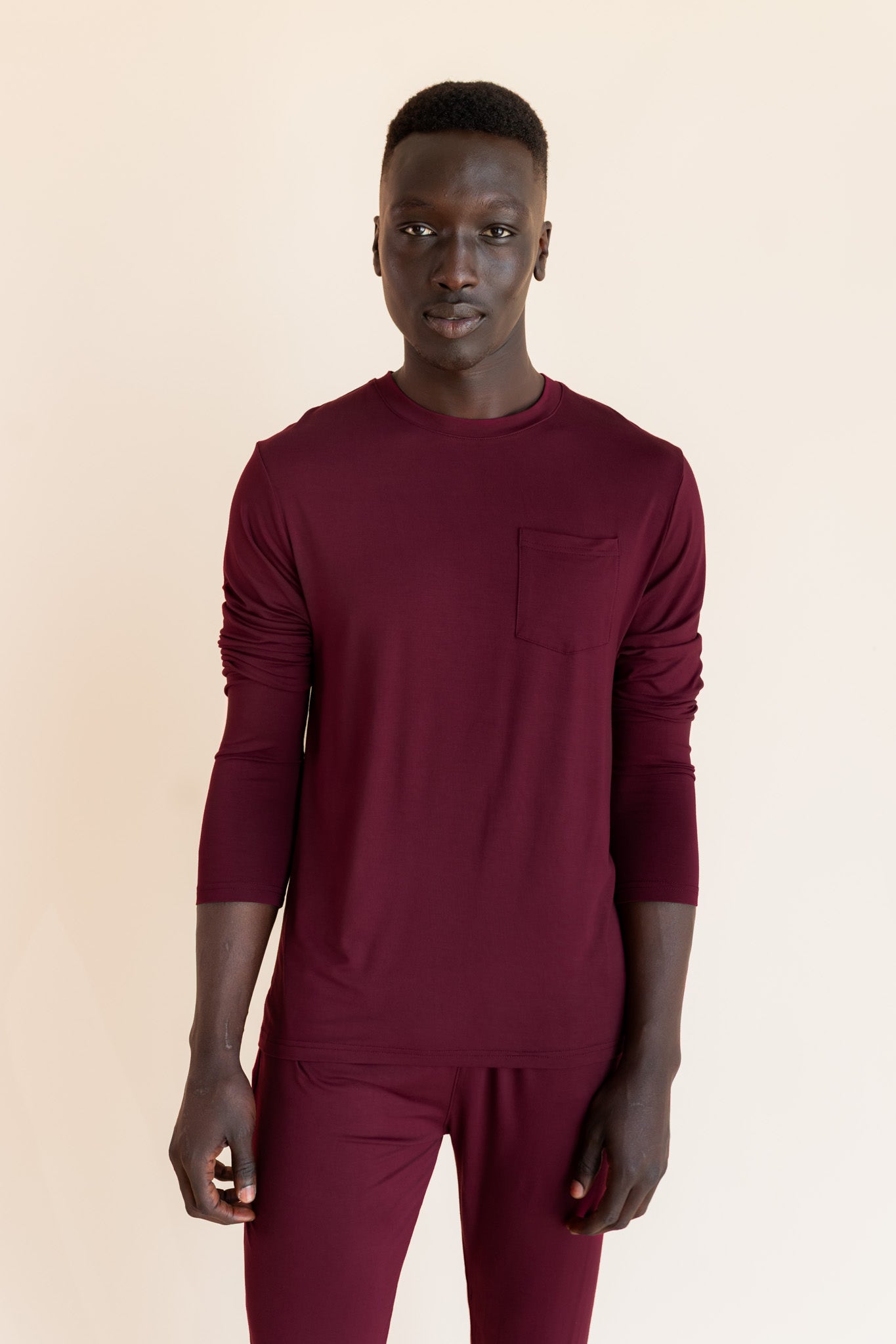 Male model wearing burgundy jogger set in a studio setting, rolled up sleeves