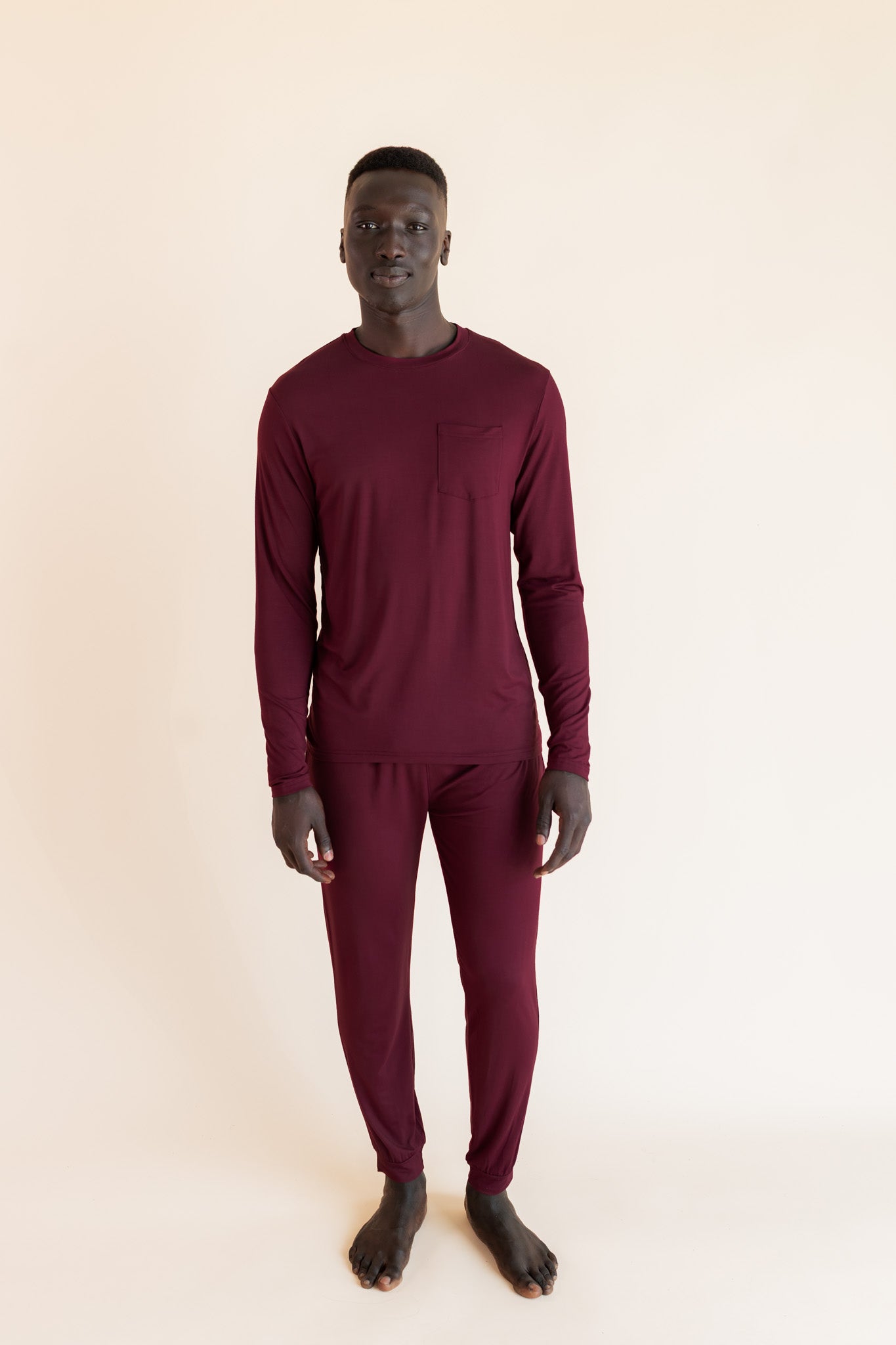Male model wearing burgundy jogger set in a studio setting