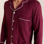 Close up of Model wearing Men's Long Sleeve Pajama Set in Burgundy with cloud trim on a beige background