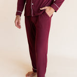 Model showcasing the pockets of Men's Long Sleeve Pajama Set in Burgundy on a beige background