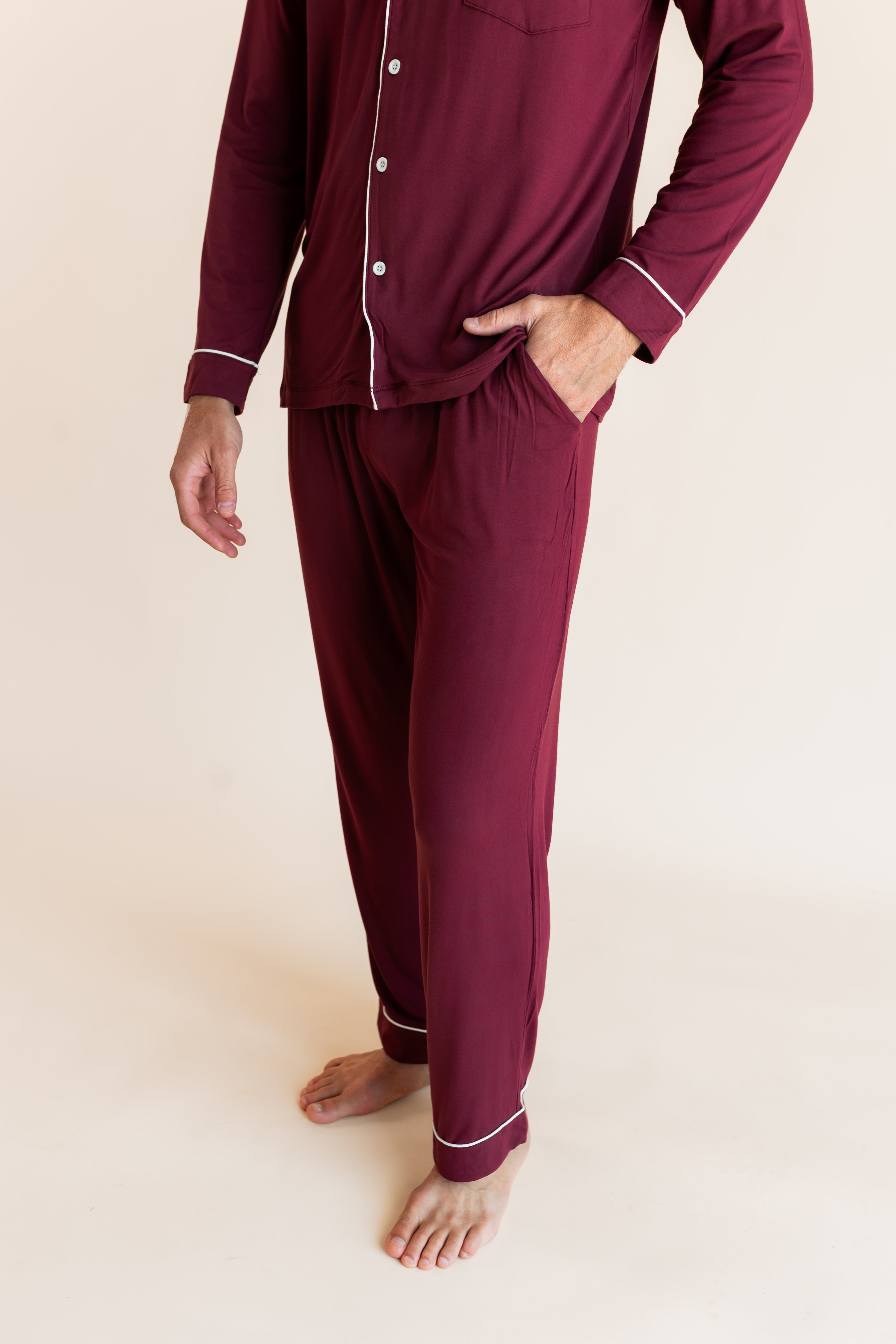 Model showcasing the pockets of Men's Long Sleeve Pajama Set in Burgundy on a beige background