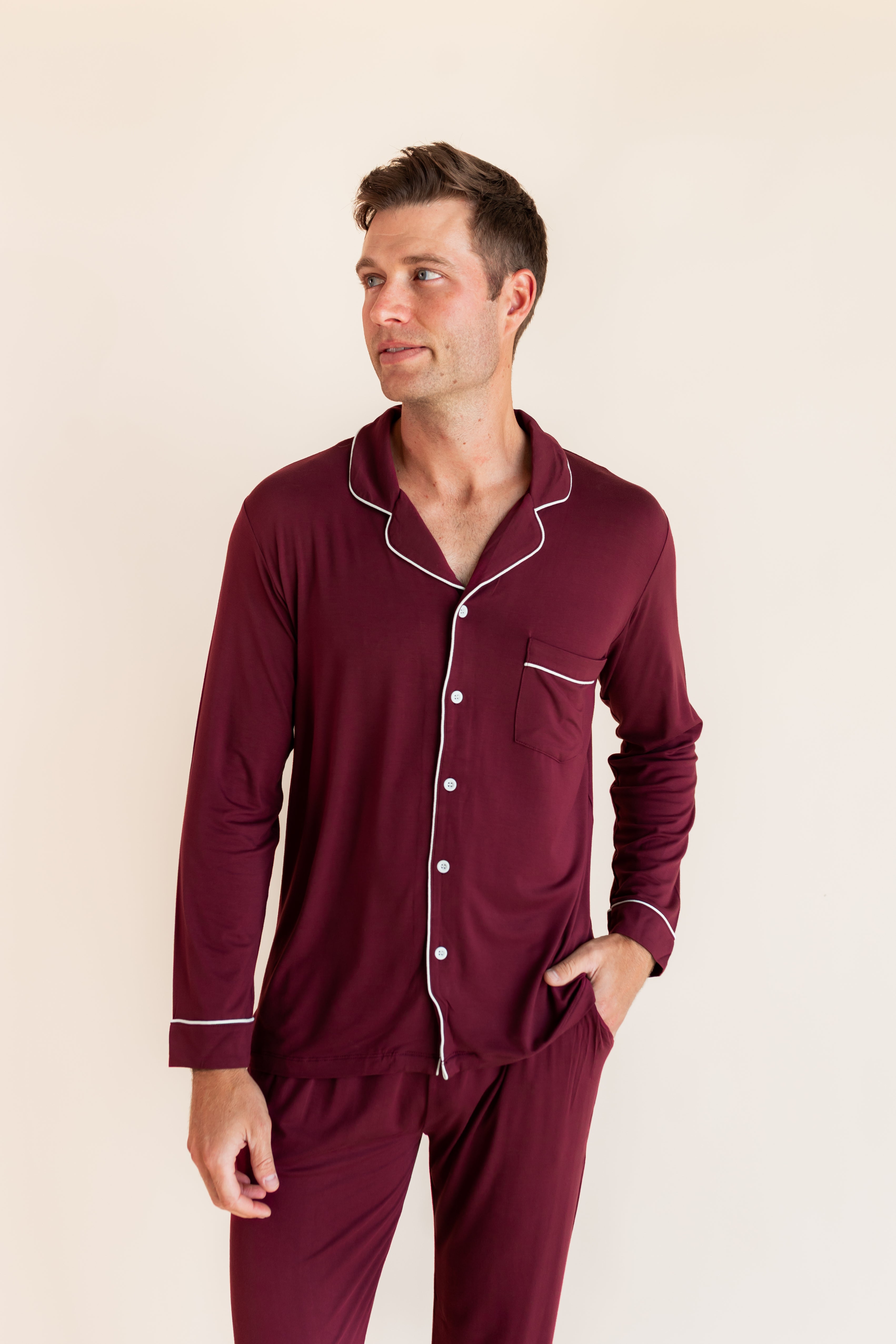 Model wearing Men's Long Sleeve Pajama Set in Burgundy with pockets on a beige background