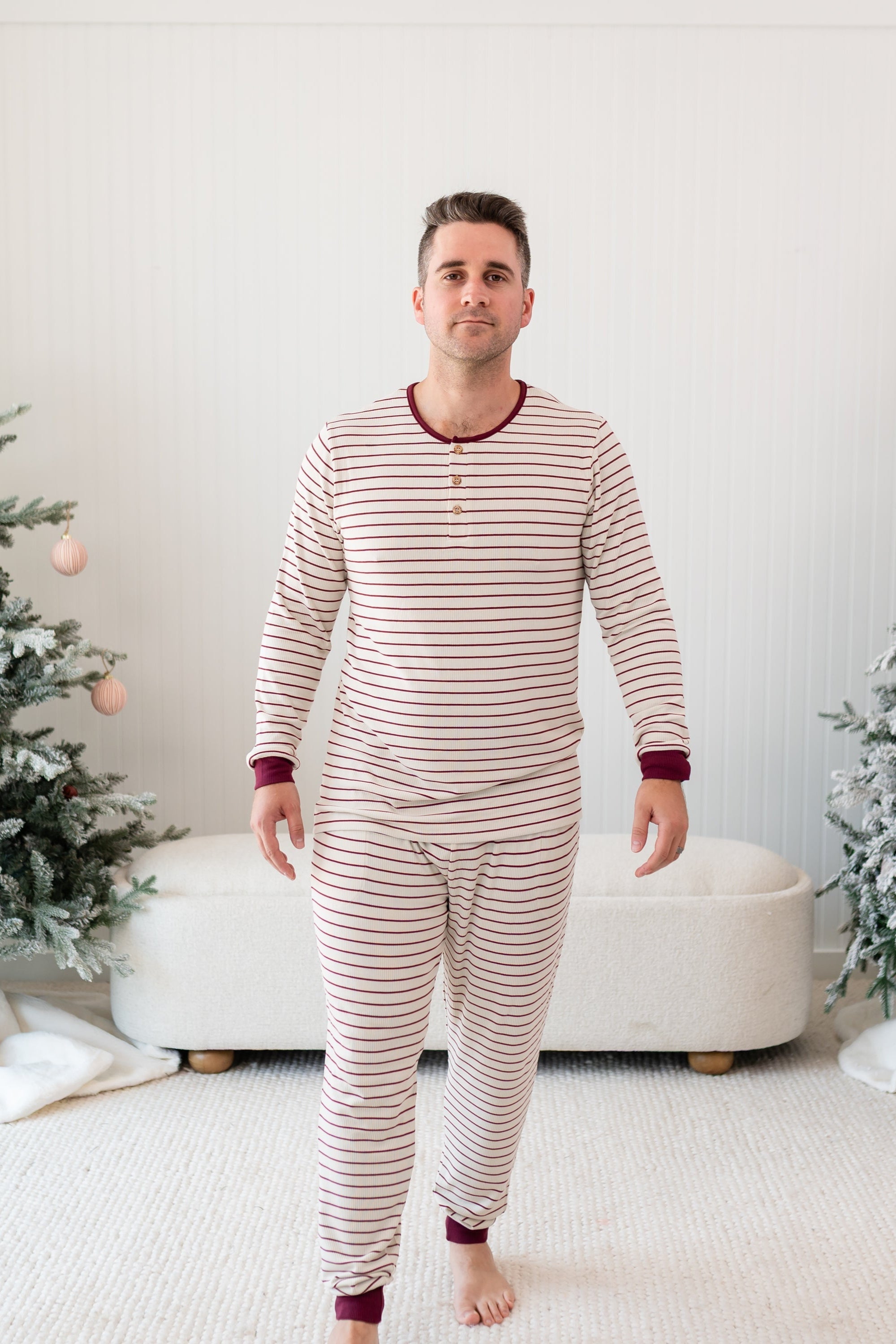 Male walking wearing the Men's Ribbed Henley Set in Burgundy Stripe in front of a Christmas themed backdrop