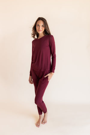 Woman modeling a jogger pajama set in a burgundy color in a studio setting