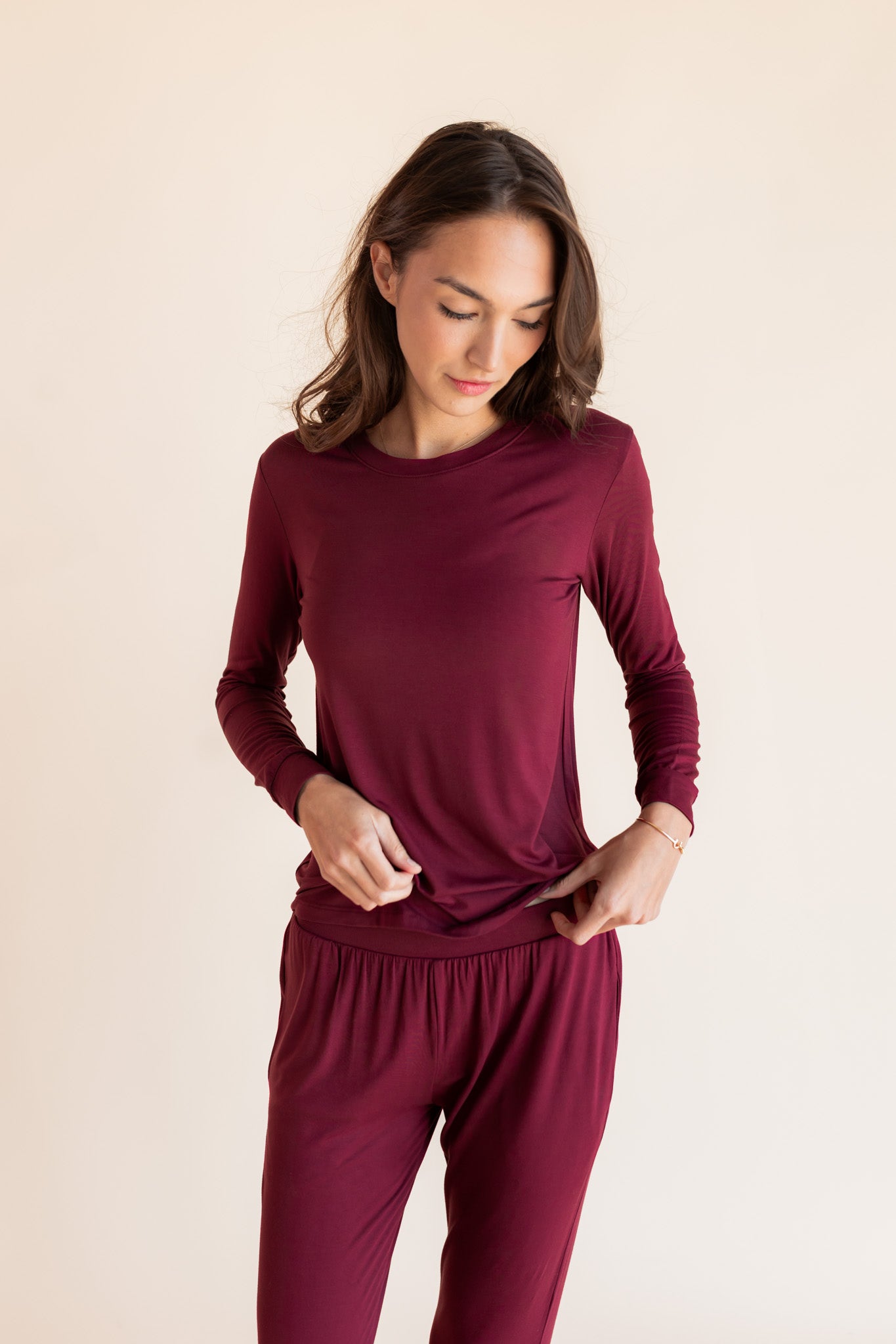Woman modeling a jogger pajama set in a burgundy color in a studio setting, showing waist band