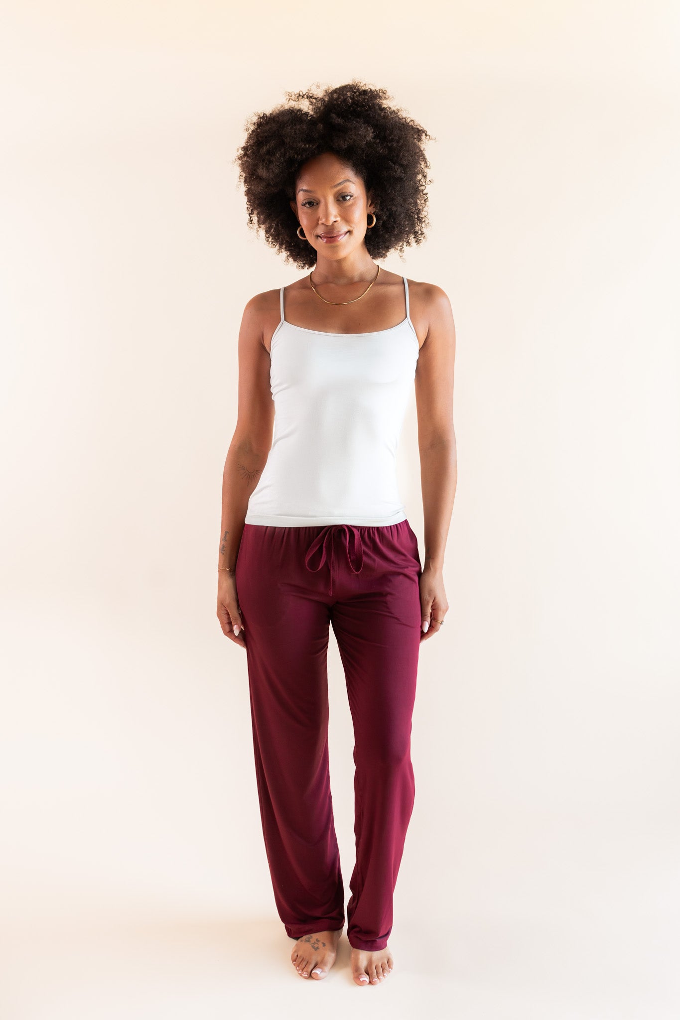 Modal posing in Women's Lounge Pants in Burgundy under white camisole on a beige background