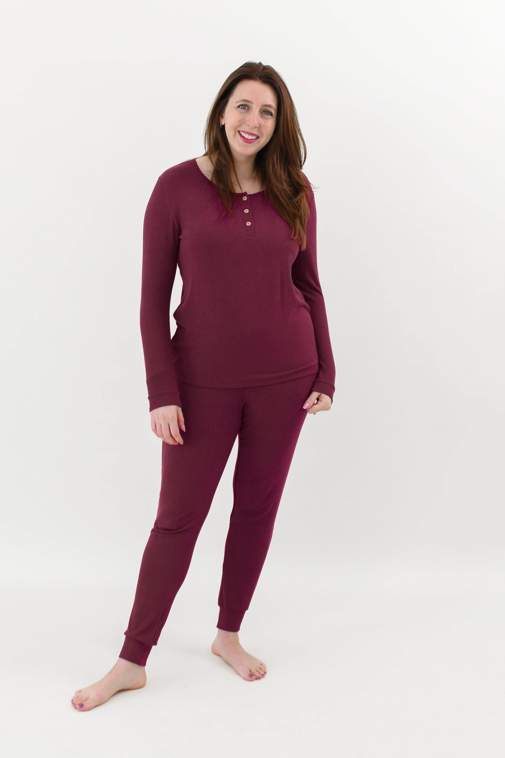 Smiling female model wearing the Women’s Ribbed Henley Set in Burgundy in front of a light colored back drop