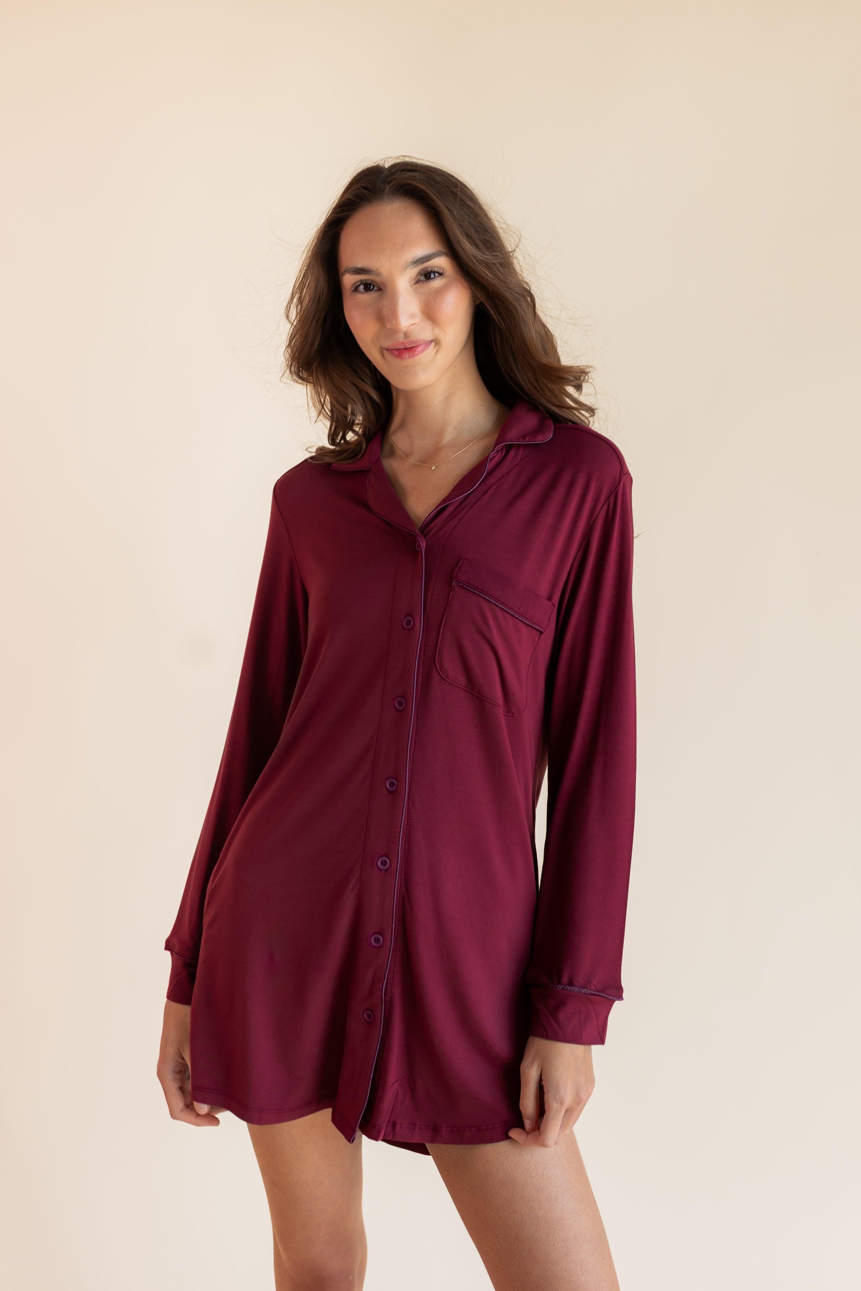 A woman modeling a long-sleeve button-front shirt dress in deep burgundy against a plain beige studio background.
::: Model is 5'9.5" wearing size XS ///