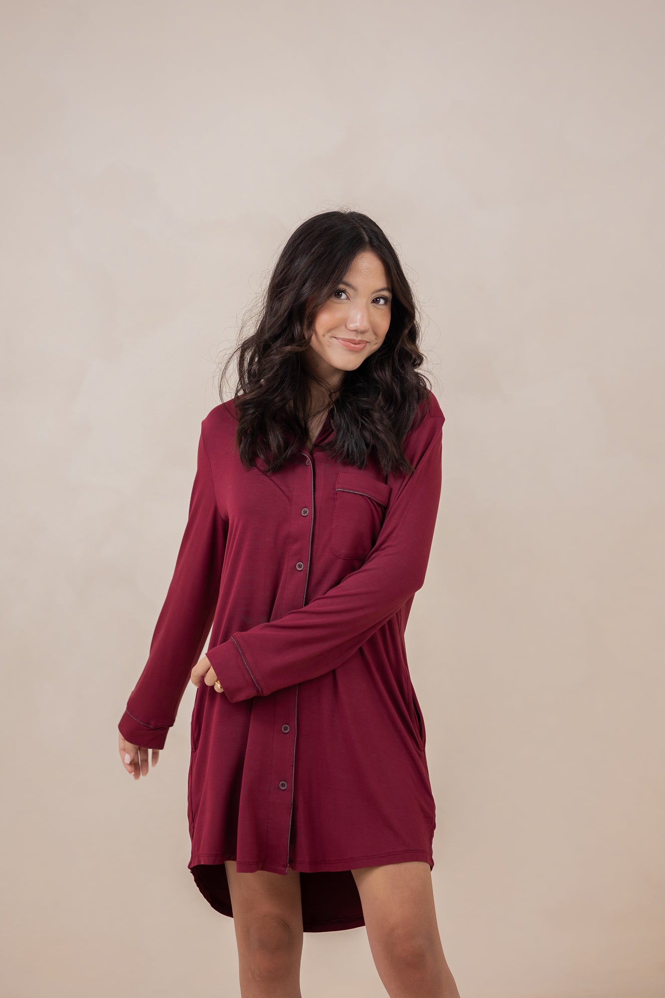Woman modeling the Kyte Women's Sleep Shirt in Burgundy with arm crossed across her waist
