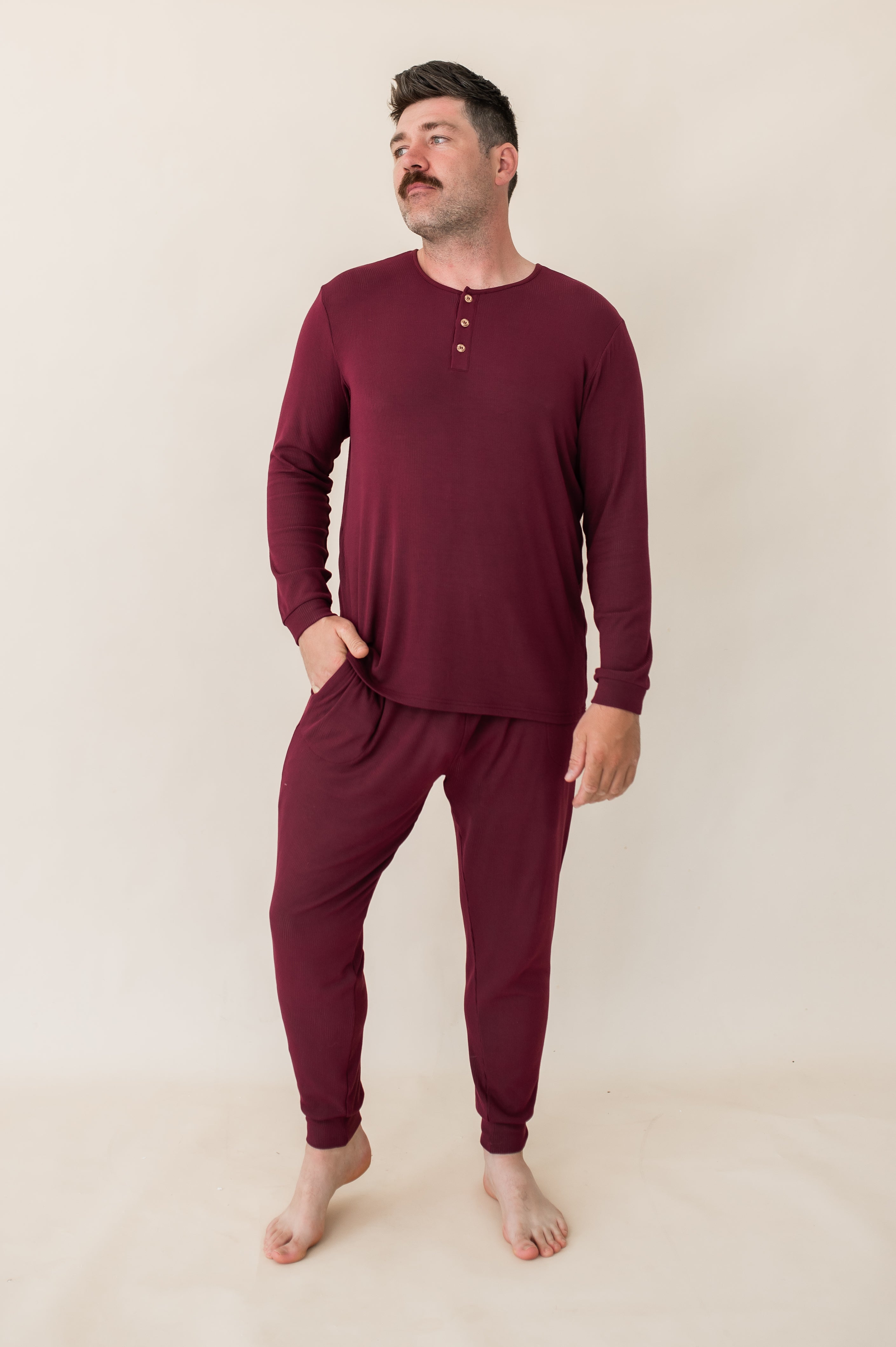 Model looking to the side with hand in pocket while wearing the Men's Ribbed Henley Set in Burgundy