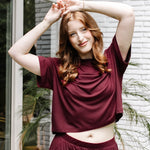 Woman with hands on her head while modeling the Women's Short Sleeve Tee in Burgundy