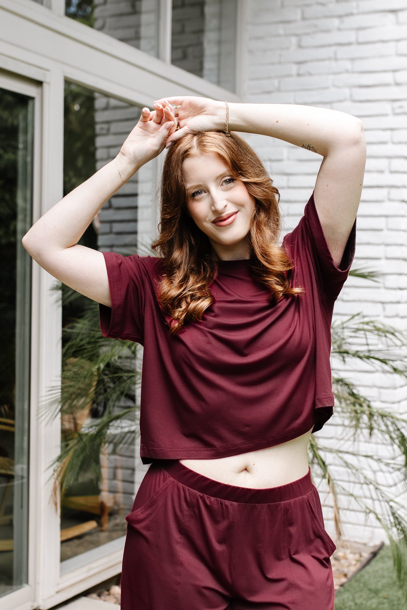 Woman with hands on her head while modeling the Women's Short Sleeve Tee in Burgundy