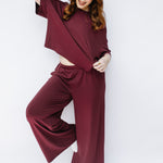 Model with hand in hair while wearing the Women's Short Sleeve Tee in Burgundy paired with matching wide leg pants
