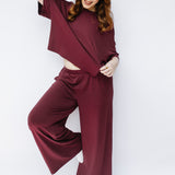 Model with hand in hair while wearing the Women's Short Sleeve Tee in Burgundy paired with matching wide leg pants