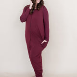 Smiling woman looking to the side while modeling the Kyte Adult Sleep Bag Walker in Burgundy with matching top beneath it