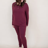 Woman looking downwards and smiling while modeling the Kyte  Long Sleeve Henley top in Burgundy 