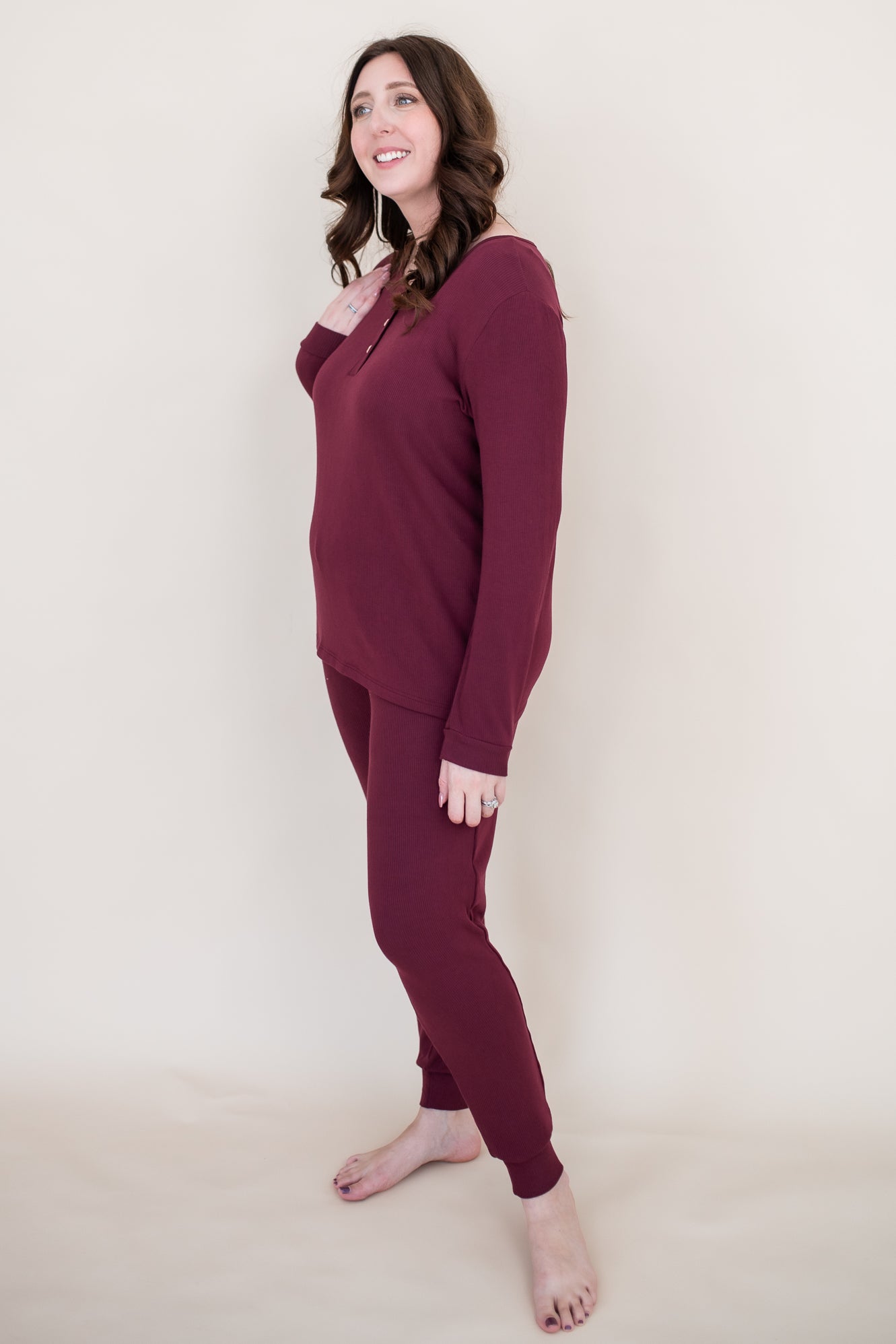 Model looking to the side while wearing the Women's Henley top in Burgundy paired with matching joggers